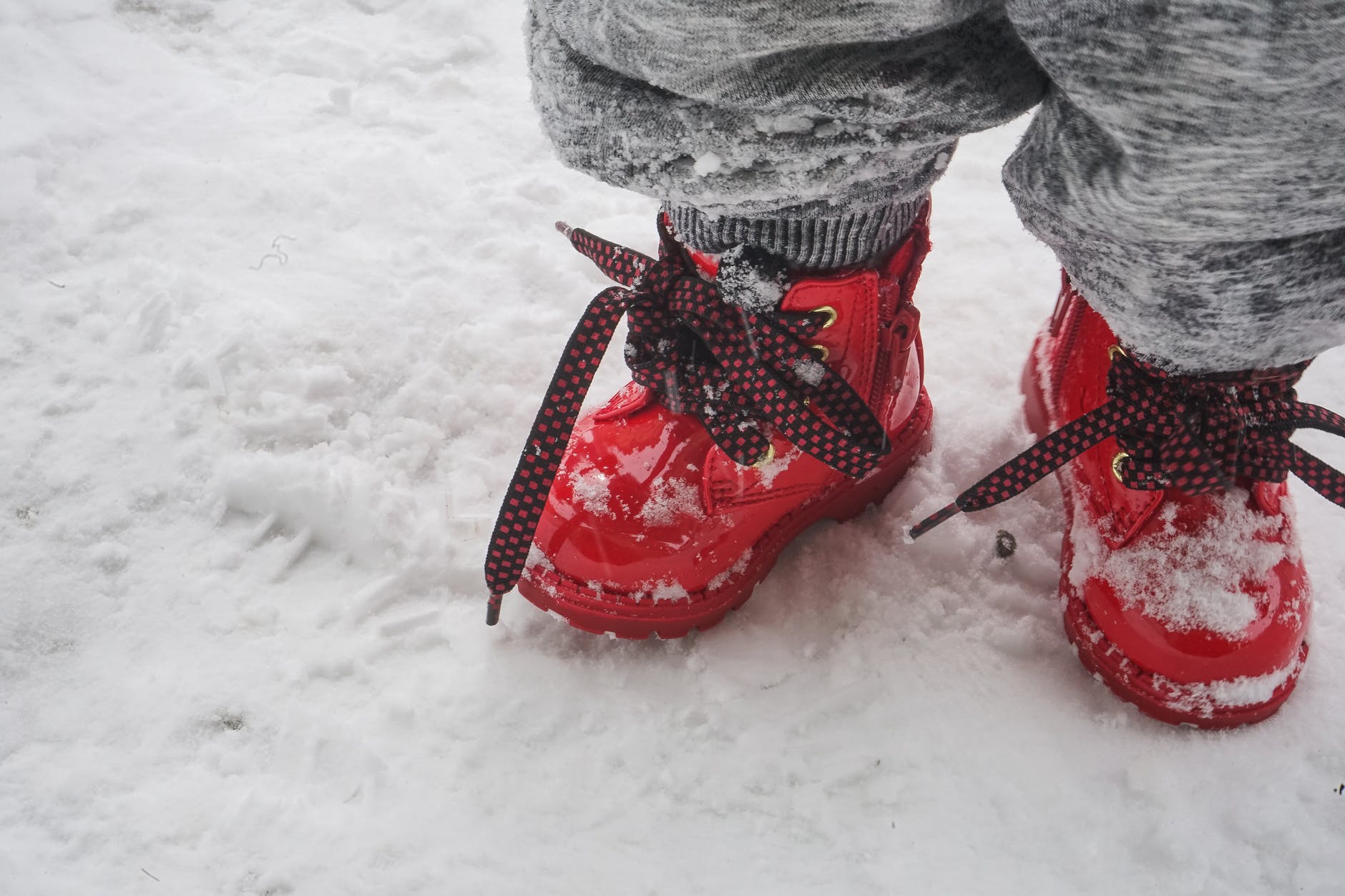 toddler wearing red shoes standing on snow